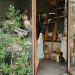 Azjatycka florystka odwraca tabliczkę otwarte/zamknięte przy wejściu do sklepu