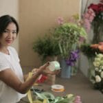 Uśmiechnięta florystka w swoim sklepie przed ladą z kwiatami