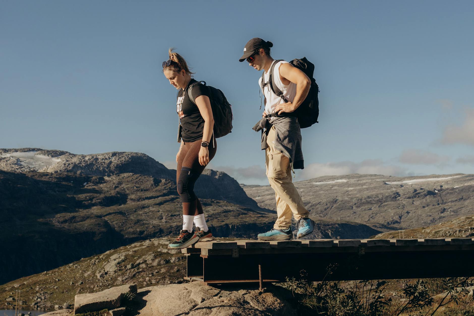 Dwójka turystów z plecakami na drewnianym moście w górskim krajobrazie