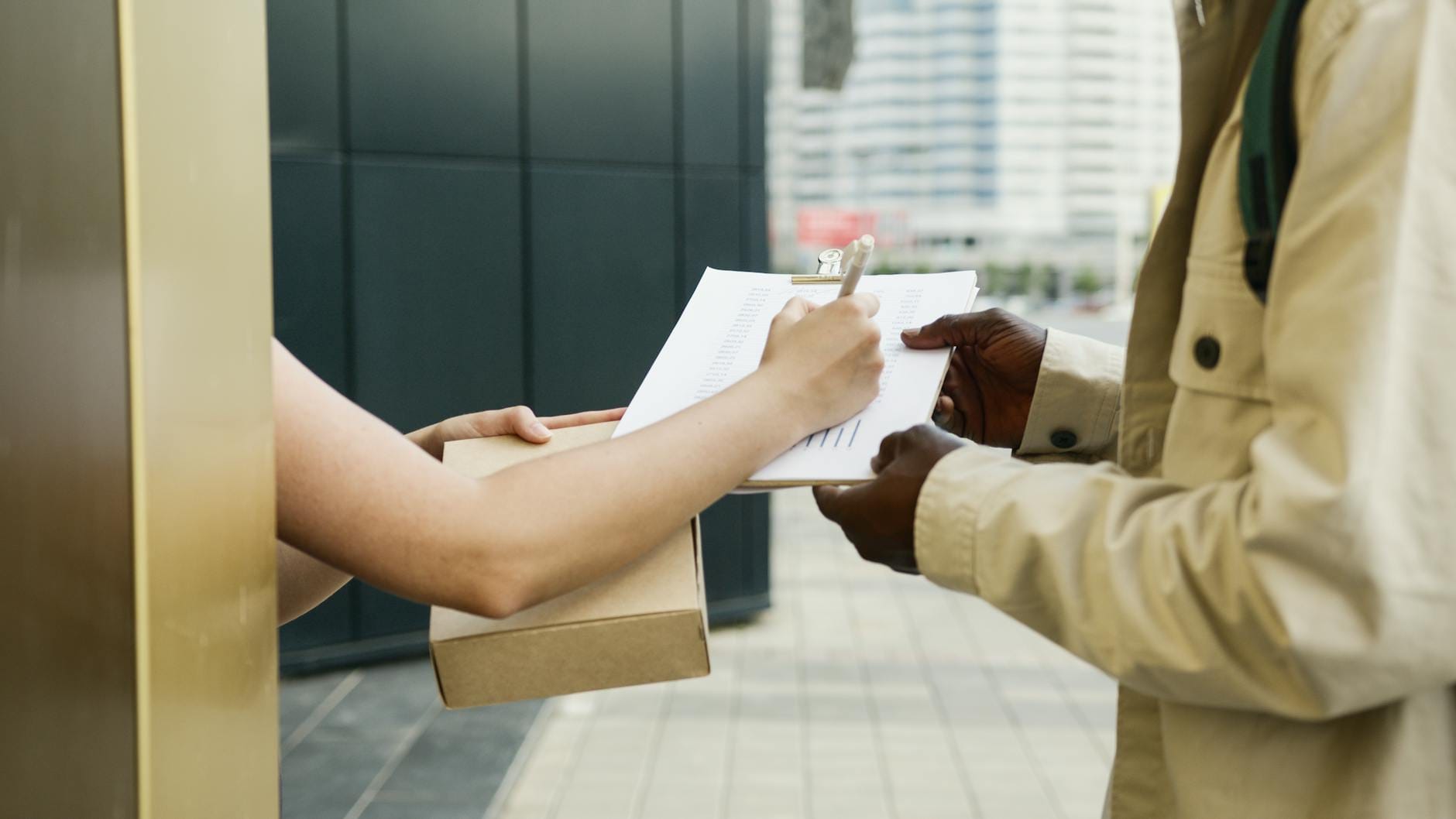 Kurier doręcza paczkę, klient podpisuje potwierdzenie odbioru na dworze