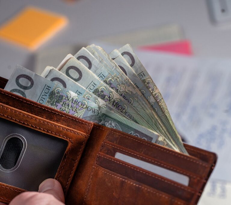 Brązowy portfel z banknotami złotowymi na zagraconym biurku